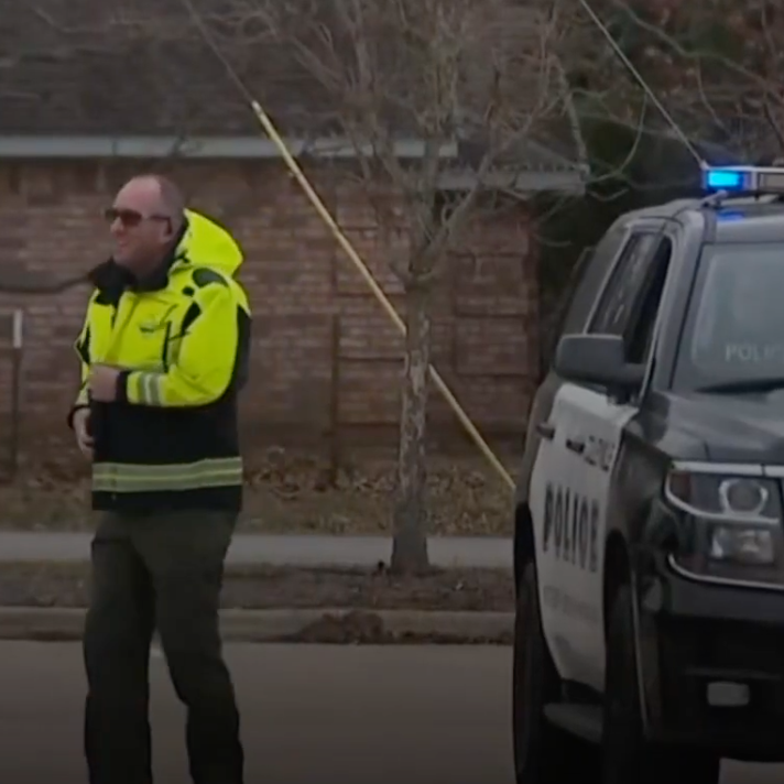 A police officer in yellow vest outside police car