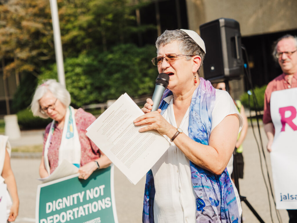 Rabbi Toba Spitzer speaks into a microphone at aprotest for immigration rights in boston